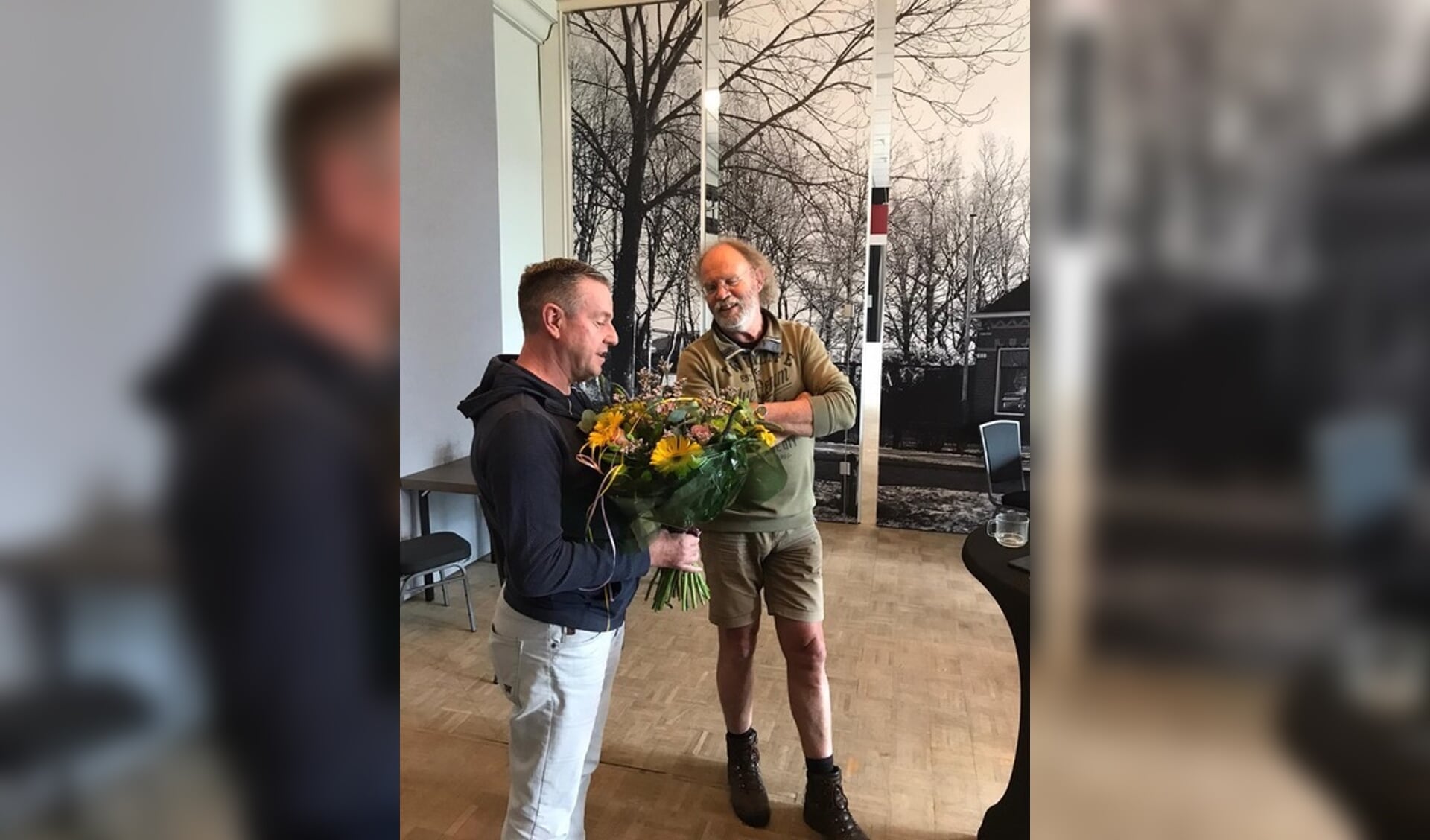 Kees Koudstaal (rechts op de foto) op zijn laatste werkdag. Hij krijgt bloemen uit handen van Teake Vaartjes - vice voorzitter Stichting Sociaal Cultureel Werk Burgum.

