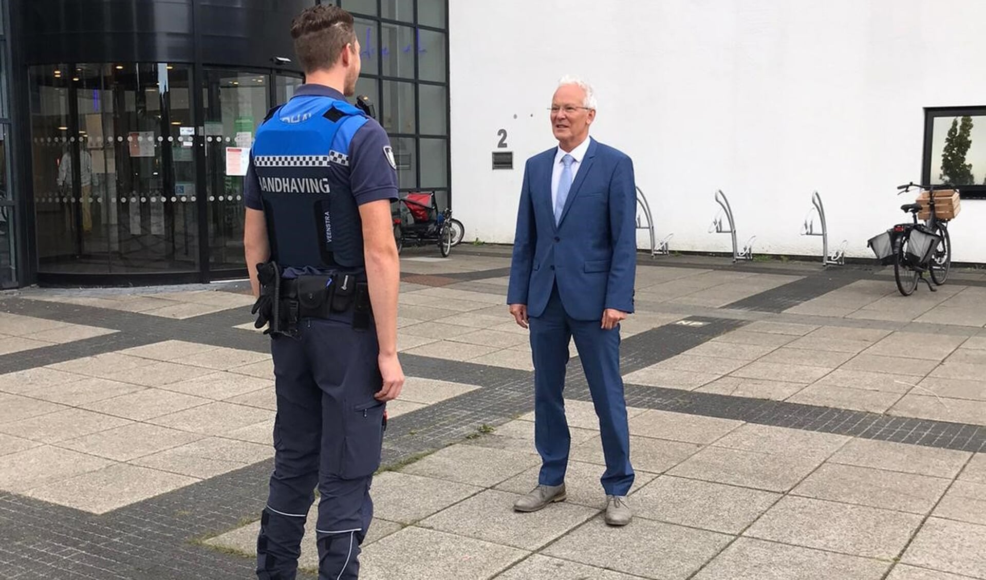 Burgemeester Jan Rijpstra met op de voorgrond een buitengewoon opsporingsambtenaar (boa). Scan de foto met de ActiefPlus-app voor een filmpje waarin de burgemeester vertelt over veiligheid in Drachten.