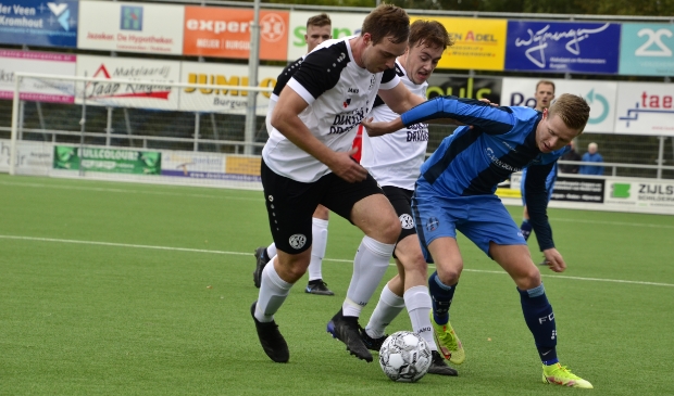 <p>Harmen Vlietstra van FC Burgum in een fel duel met de verdediging van Drachtster Boys. </p>
