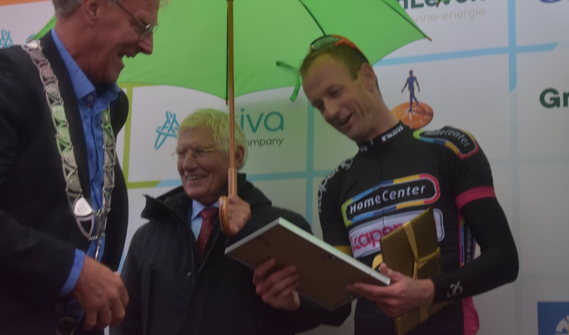 Pieter Weening leest verrast dat hij ereburger is geworden van Achtkarspelen. Links burgemeester Oebele Brouwer, in het midden sponsor Piet Kapenga.
