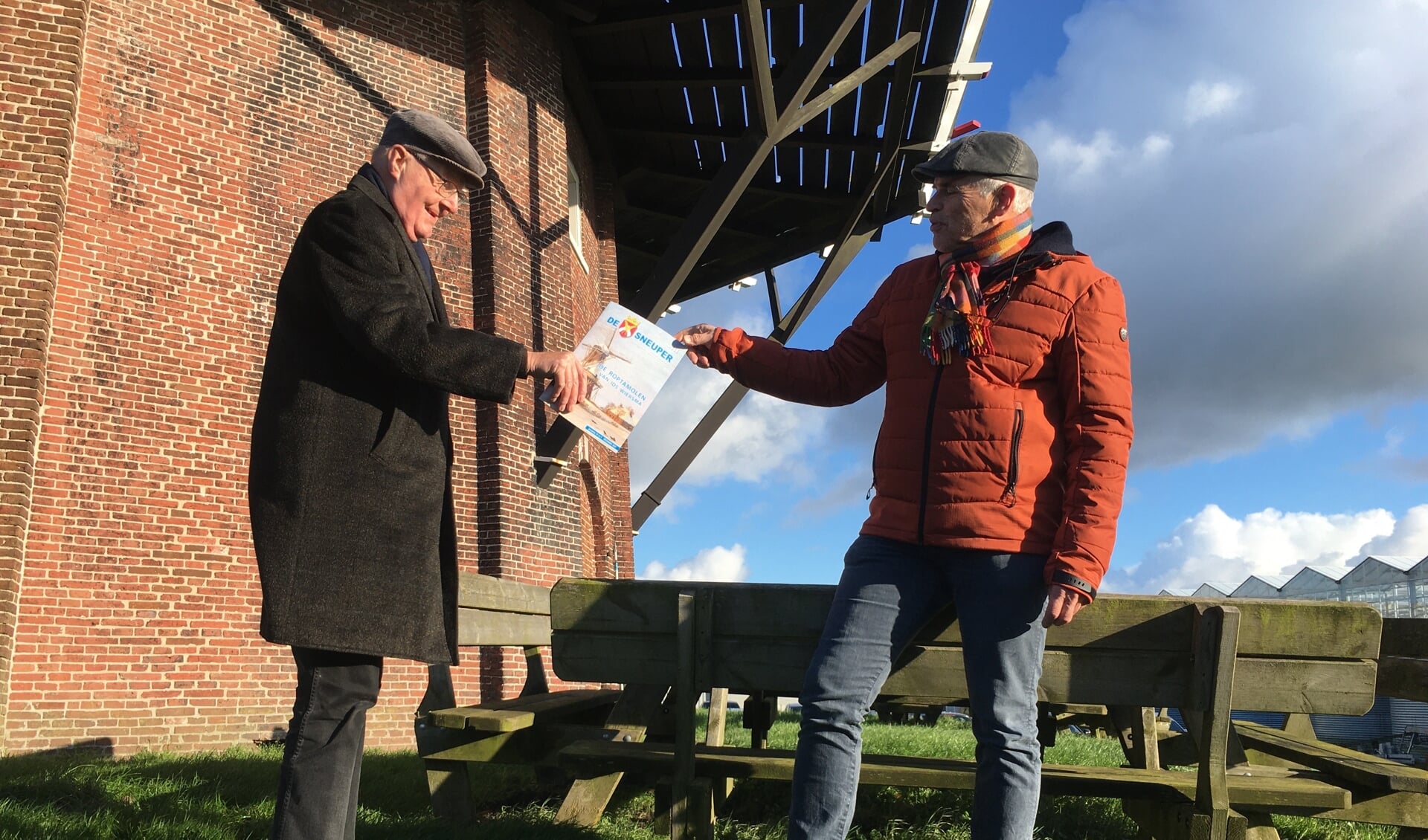 Molenaarszoon Jouke Pieter van der Heide (links) krijgt bij de Roptamolen het eerste exemplaar van het nieuwe nummer van De Sneuper, uit handen van Warner B. Banga.