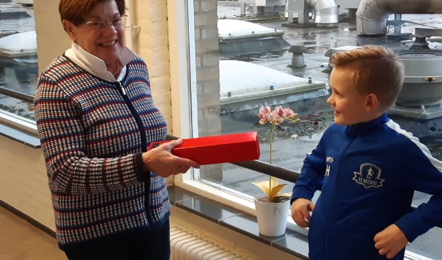 Mevrouw Van der Bijl is blij met het cadeau van Ruben Hoekstra van JO8-1 van VV Buitenpost. 
