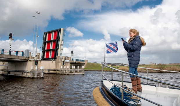 Gedeputeerde Avine Fokkens-Kelder van de provincie Fryslan, opende op een boot met haar telefoon via de app Watersport de brug.