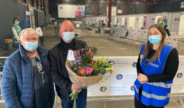 <p>GGD-medewerker Jantina Siegersma overhandigt de heer Dries van der Horst (73) uit Stiens een boeket bloemen. Met zijn vrouw kwam hij voor zijn eerste vaccinatieafspraak naar de Friese hoofdstad.</p>
