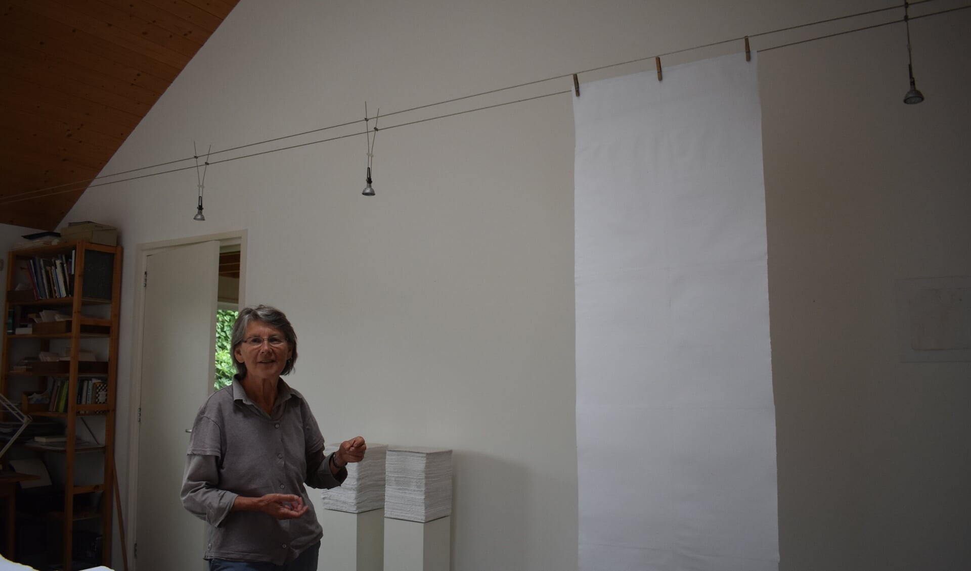 Lisette Durenkamp in haar atelier in Oostrum. De hangende baan van zelf geschept papier komt met meer in de kerk van Jouswier te hangen.