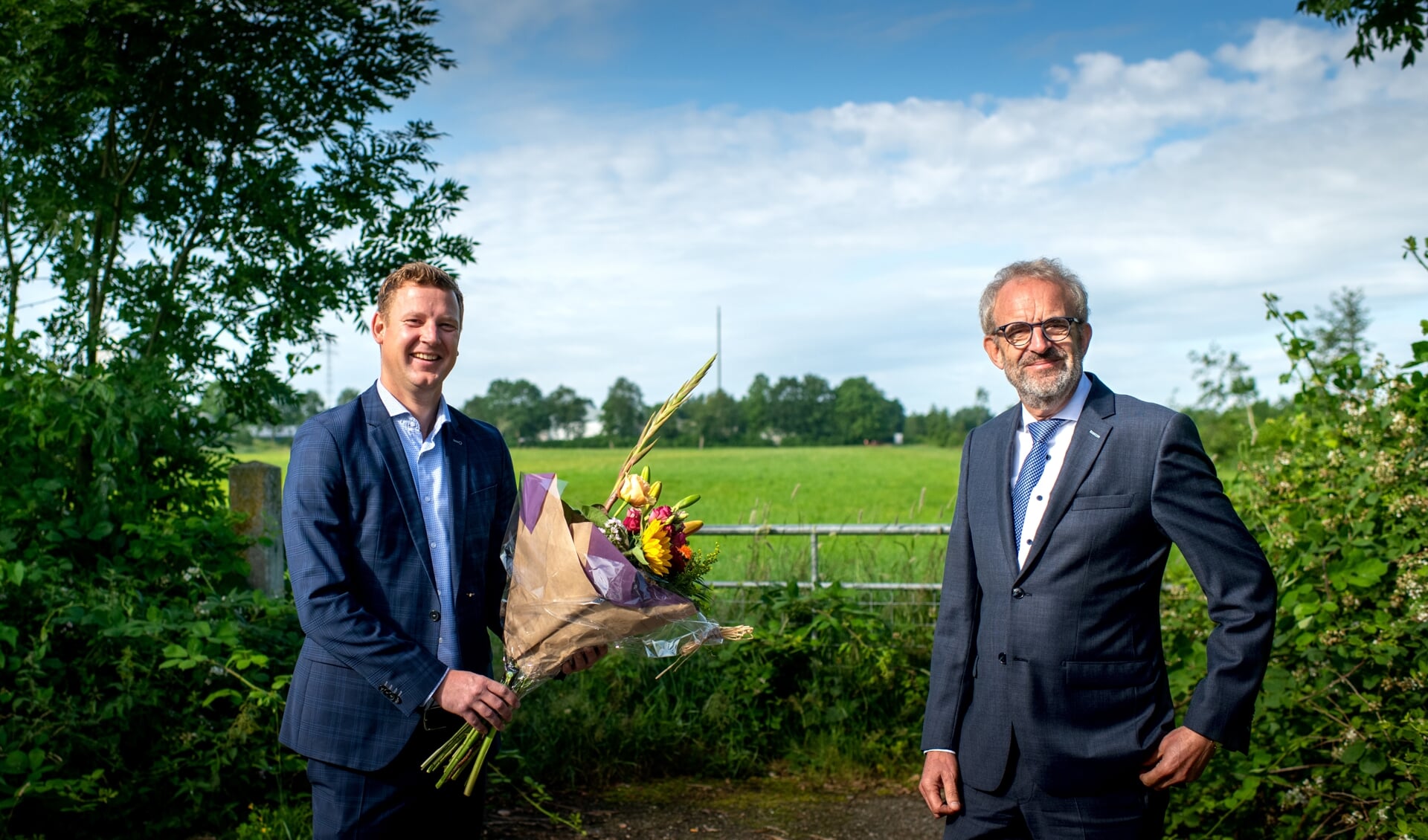 Wethouder Jouke Spoelstra (links) met bloemen voor Ulbe Bijlsma van Stertil. Op de achtergrond het bewuste terrein.