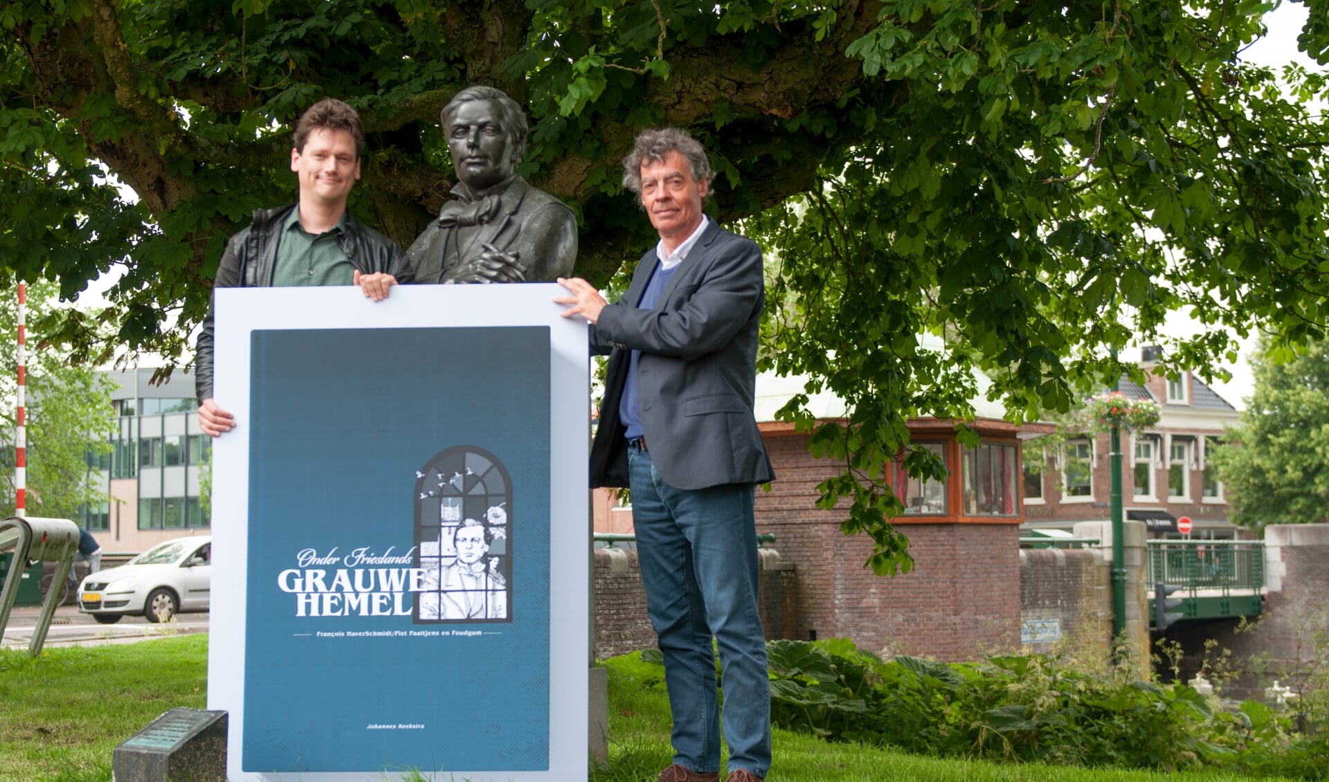 Schrijver Johannes Keekstra (links) onthult samen met uitgever Louw Dijkstra het boekomslag bij de buste van François HaverSchmidt in geboortestad Leeuwarden. 