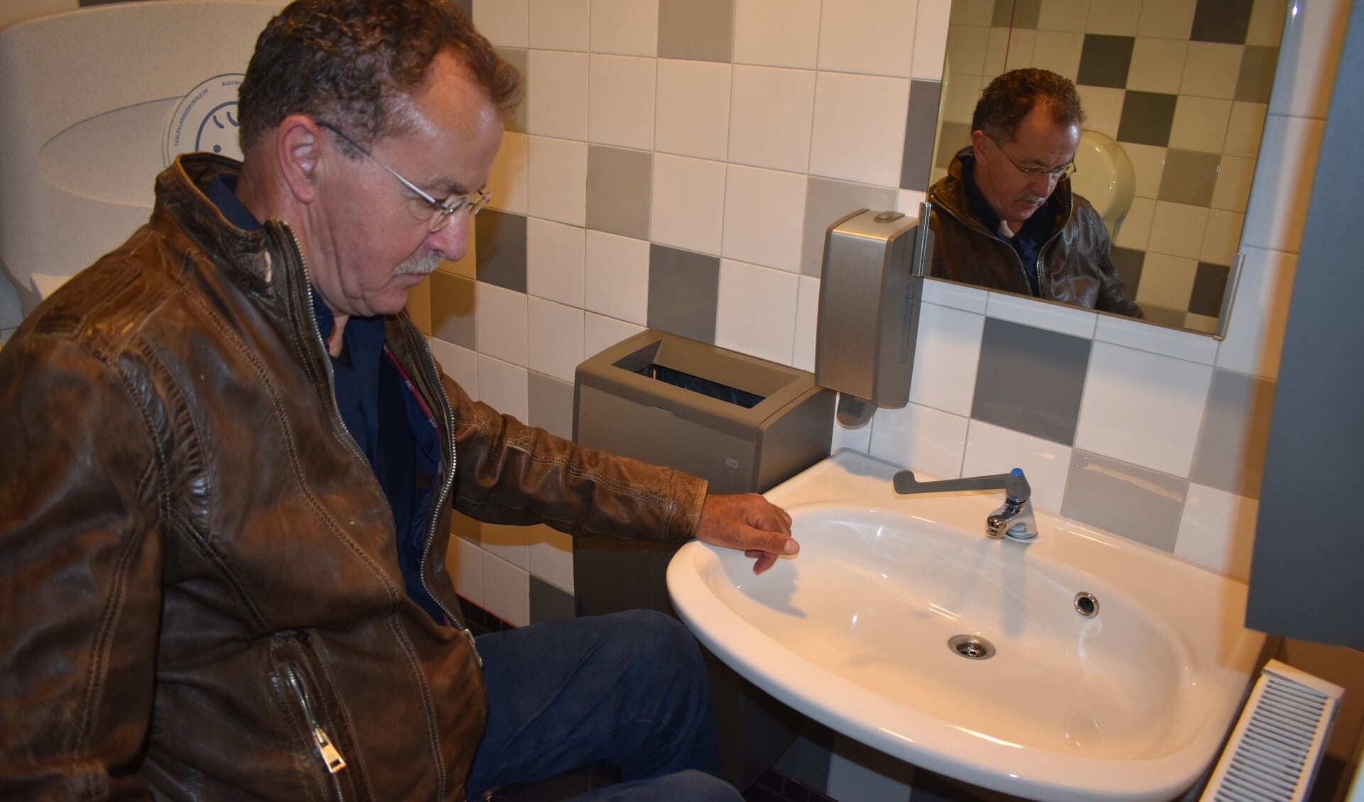 Andries Riedstra test het invalidentoilet in het gemeentehuis. De wastafel zit voor hem te laag.