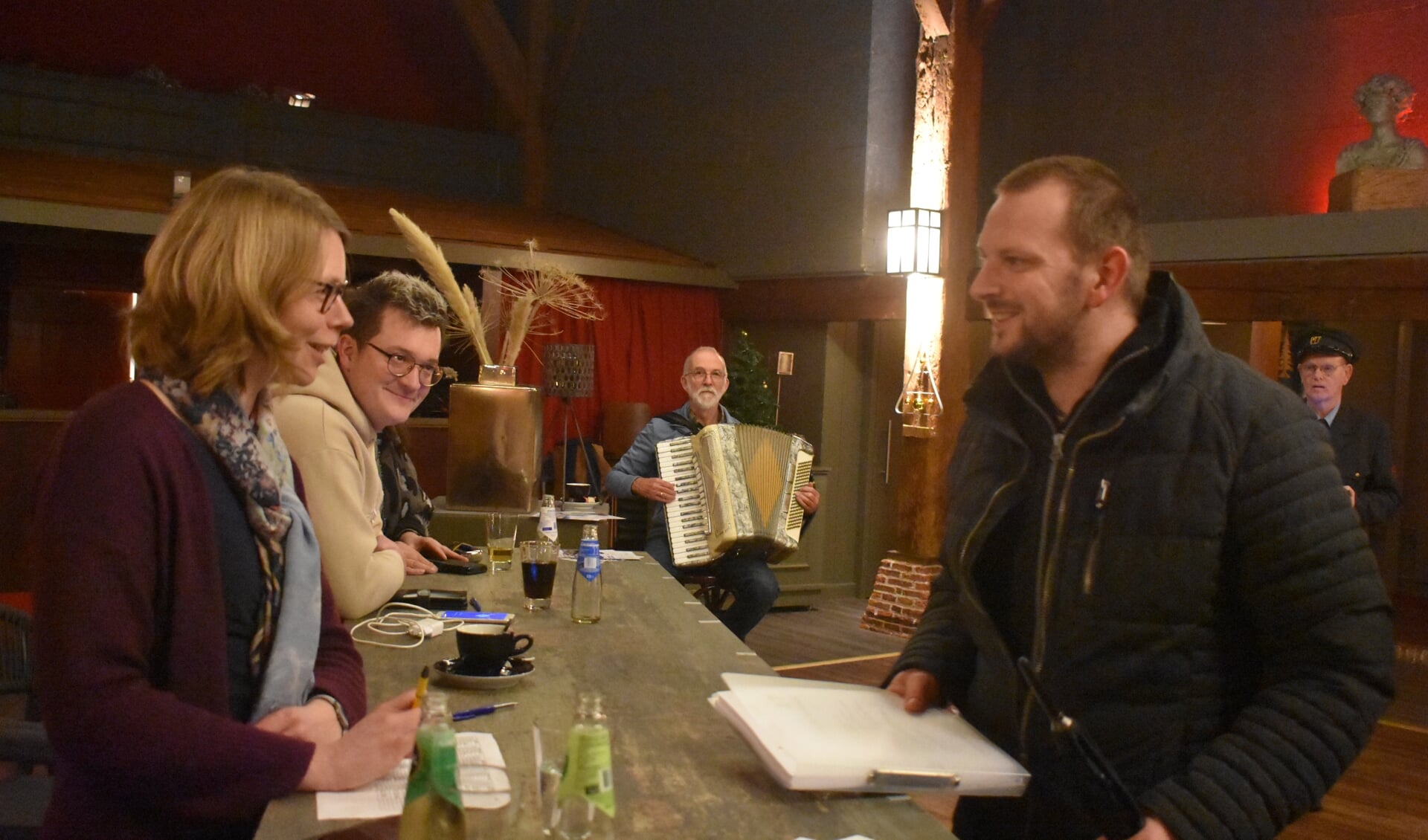 De laatste 'groepsvertegenwoordiger' (rechts voor) haalt het opdrachtenboek af in De Pleats. Muzikant Keimpe van der Meer speelt nog even een deuntje.