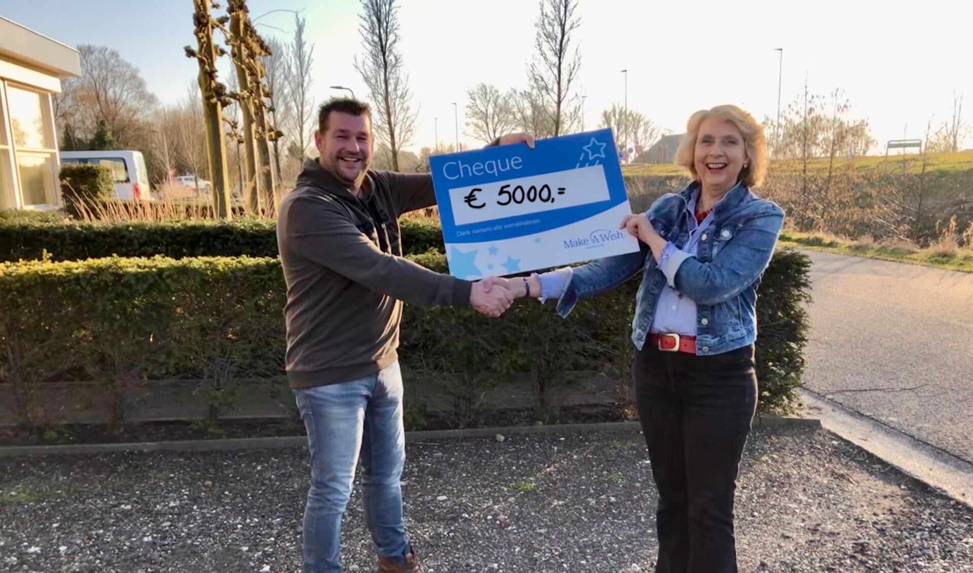 Niels Terpstra overhandigt de cheque aan Mieke Hahndiek van Make-A-Wish Nederland.