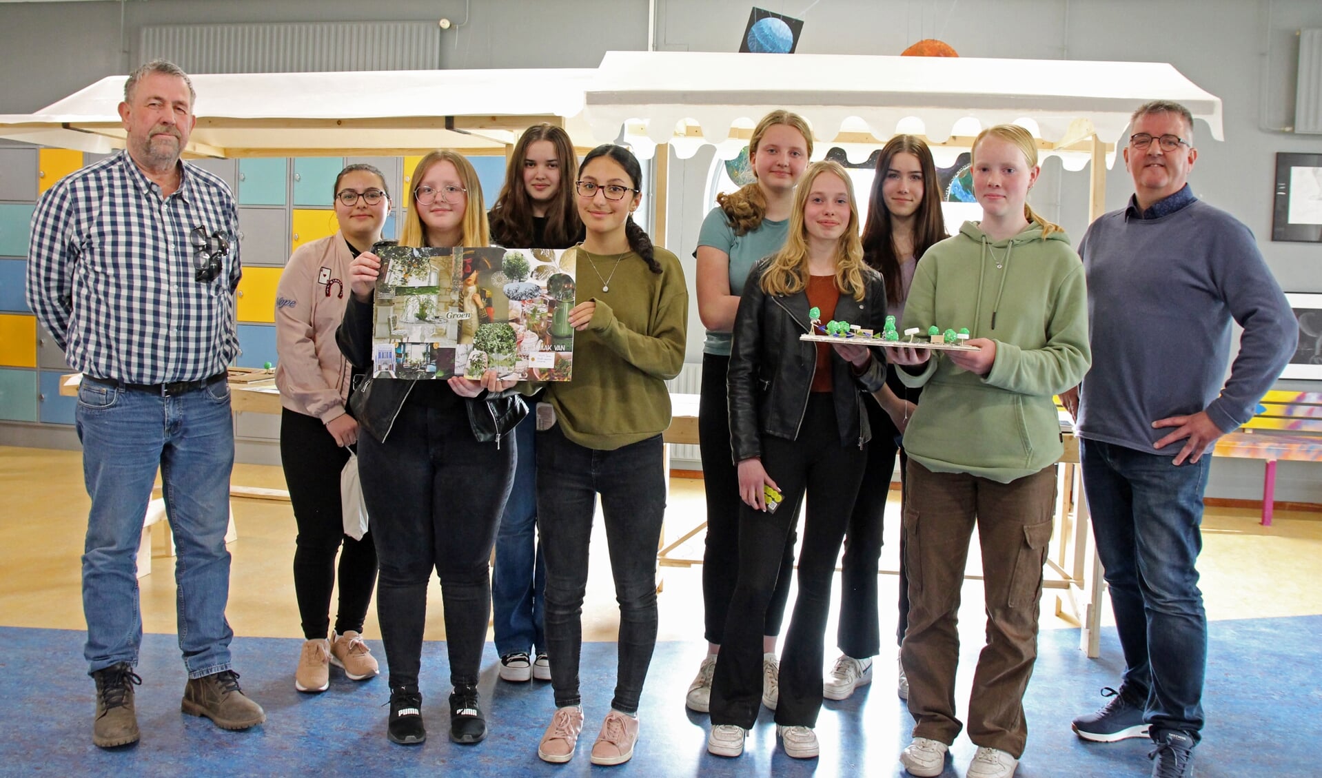 Leerlingen tonen hun winnende moodboard en maquette met ideeën voor een aantrekkelijker centrum van Buitenpost. Aan weerskanten staan Beeksma (links) en De Boer. 