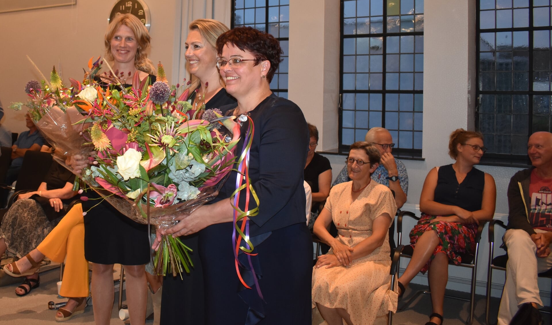 De drie beëdigde wethouders in de bloemen gezet. V.l.n.r.: Caroline de Pee (CDA), Berber van Zandbergen (GL/PvdA) en Tytsy Willemsma (FNP). Pal achter hen, in lichtgekleurde jurk, Corrie van der Linden (GL), die als nieuw raadslid werd geïnstalleerd.
