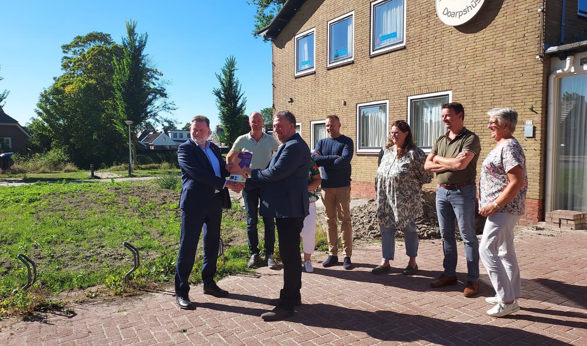 Voorzitter André Beeksma van dorpshuis De Terp ontvangt het LEADER-bordje uit handen van gedeputeerde Klaas Fokkinga. 