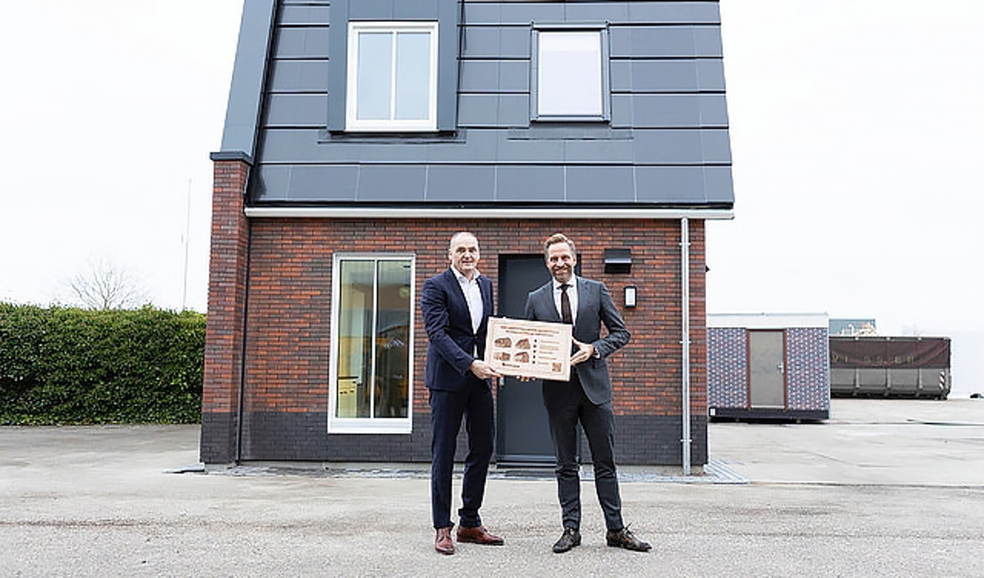 Minister Hugo de Jonge (rechts) met Biense Dijkstra bij de nieuwe houten woning op het terrein van Dijkstra Draisma in Dokkum.