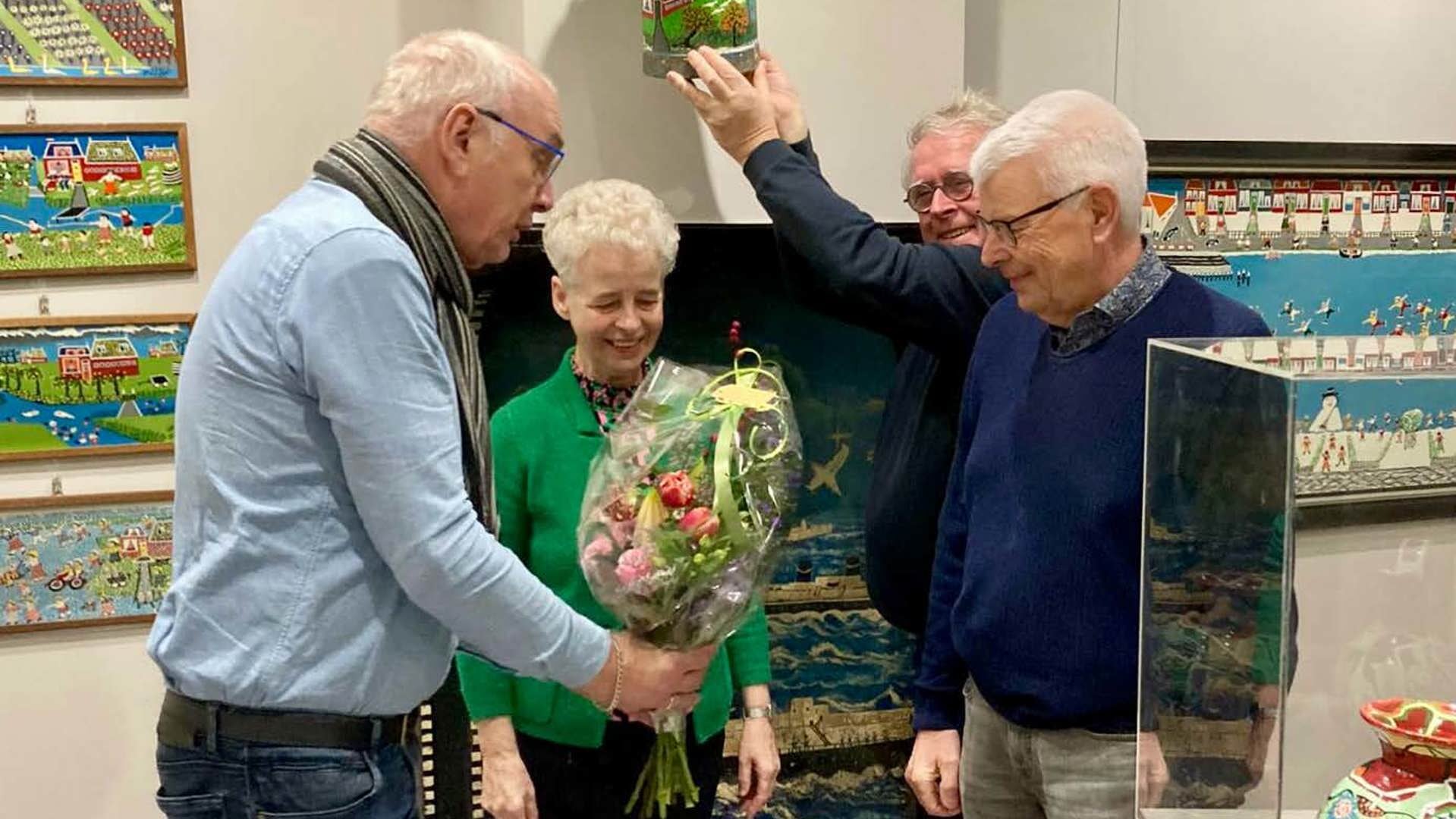 Terwijl bestuurslid Oege Hiddema het pasverworven brij-buske omhoog houdt, overhandigt museumvoorzitter
Sybren van Tuinen bloemen aan de schenkers, Elly en Jitse van der Bij uit Damwâld.