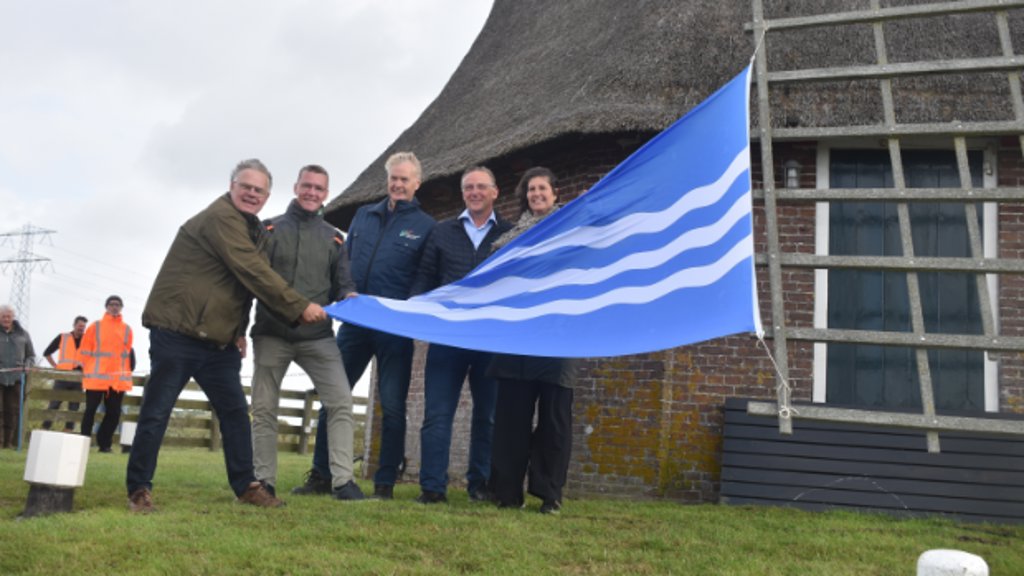 V.l.n.r.: Molenaar Willem Oosterbaan, Jeffrey Huizenga (SBB), Gerben de Boer (WF) en Gasterij-eigenaren Eduard en Sylvia Smits met de nieuwe, blauwe waarschuwingsvlag.