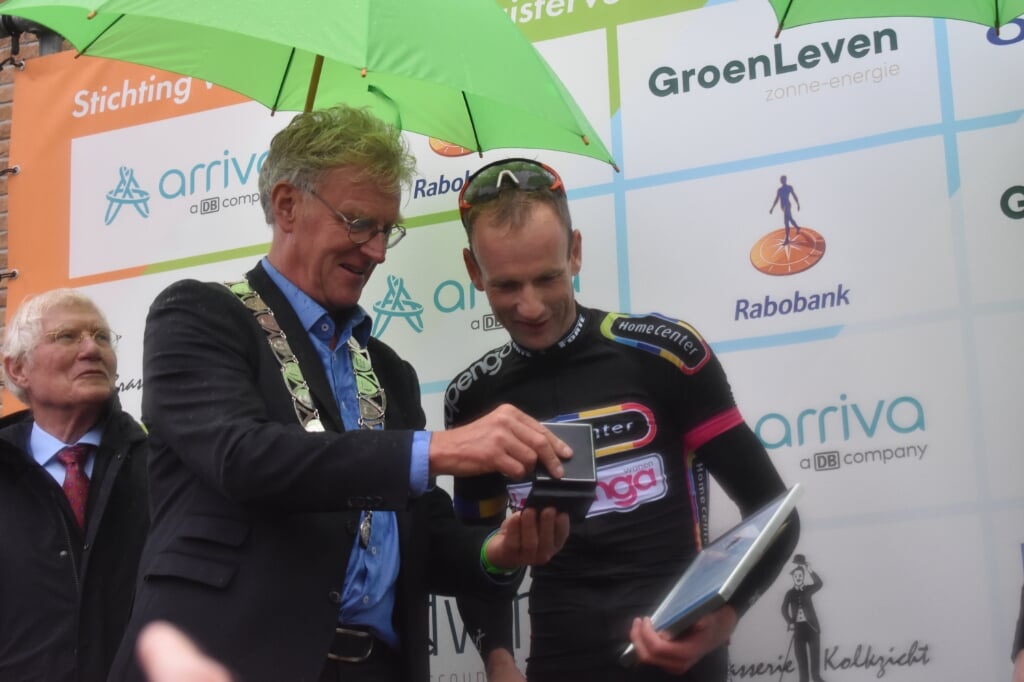 Pieter Weening bekijkt de erepenning, die burgemeester Oebele Brouwer voor hem toont. Links sponsor Piet Kapenga.