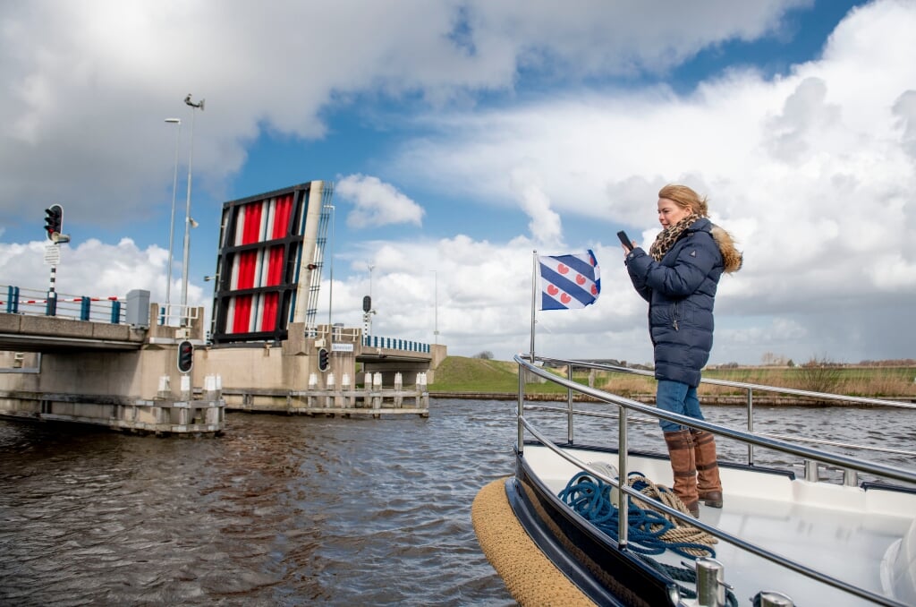 Gedeputeerde Avine Fokkens-Kelder van de provincie Fryslan, opende op een boot met haar telefoon via de app Watersport de brug.