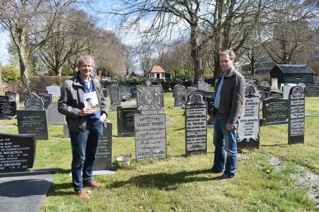 Roelof Hazelhoff (links, met het boekje) en Bé Lamberts op de Zuiderbegraafplaats in Drachten. Tussen hen in de grafsteen voor Albert Tosch.