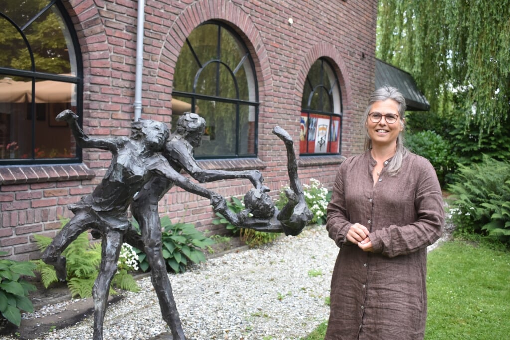 Directeur Nieske Ketelaar in de binnentuin van het Museum Dr8888. Naast haar een kunstwerk van Verkade, 1971: 'Vader en moeder met slingerend kind.'