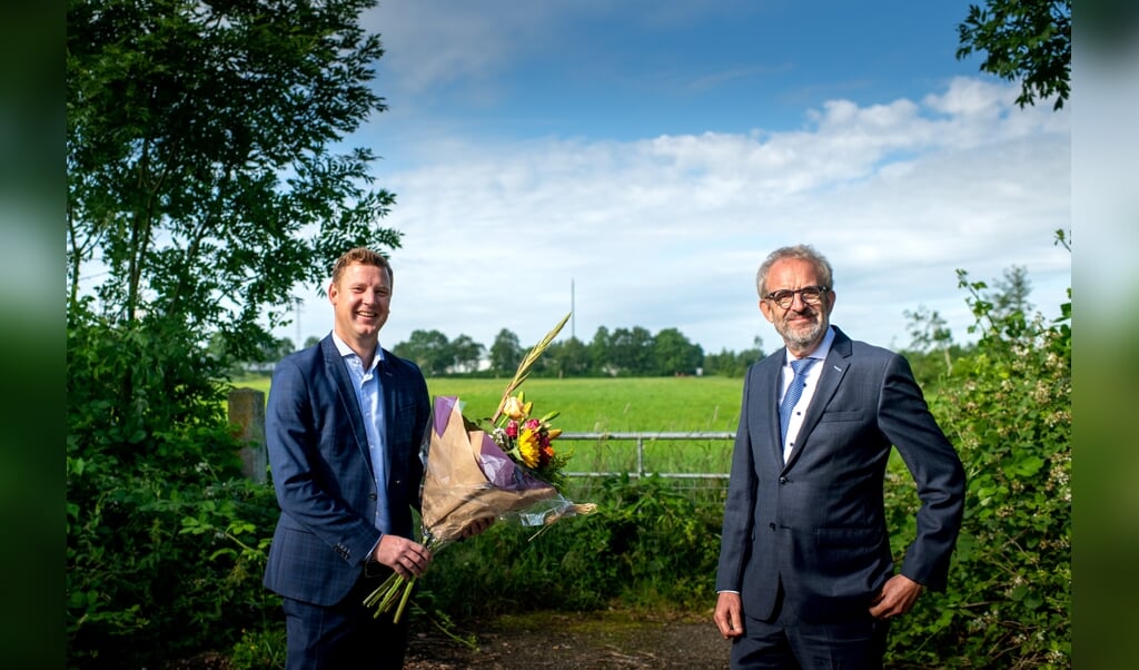 Wethouder Jouke Spoelstra (links) met bloemen voor Ulbe Bijlsma van Stertil. Op de achtergrond het bewuste terrein.