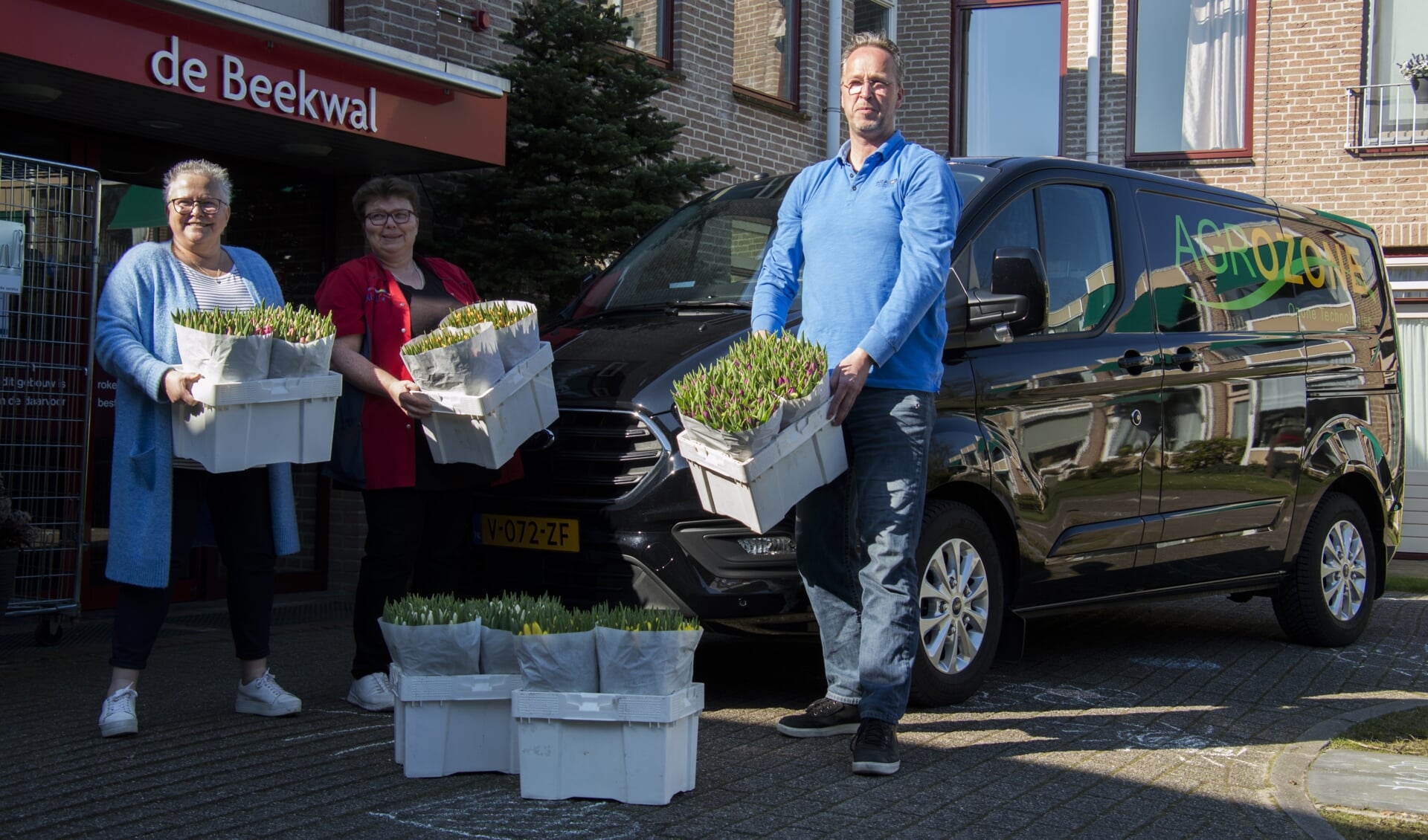 Cees de Haan overhandigt de tulpen aan twee medewerksters van de Beekwal. Foto: Marion Verhaaf