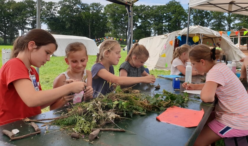 Kinderen bouwen een stationshal met materialen uit het bos.