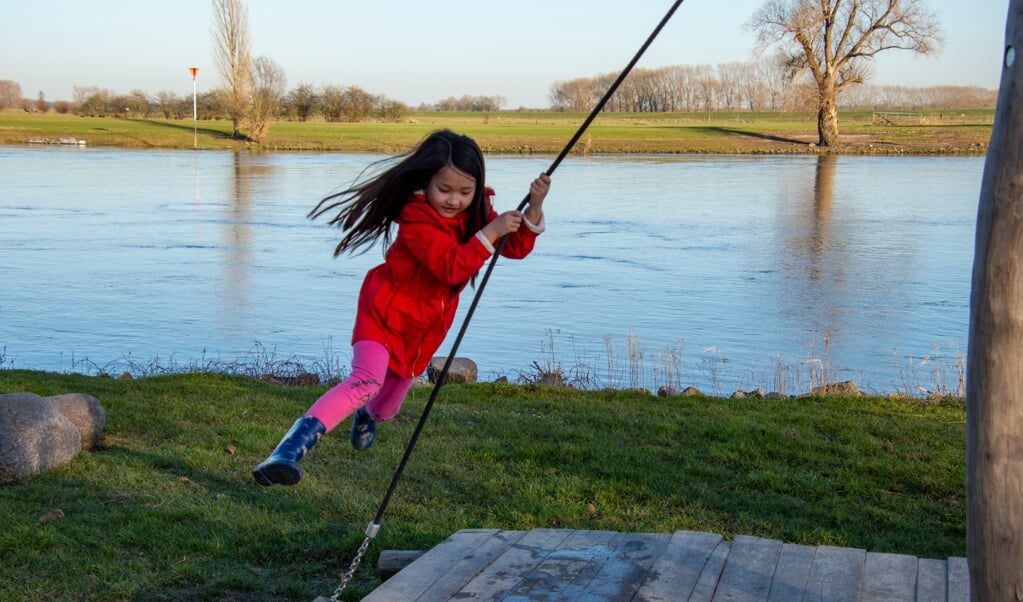 Zonder jas rondjes draaien aan het speeltoestel bij de IJssel. Foto: Marion Verhaaf