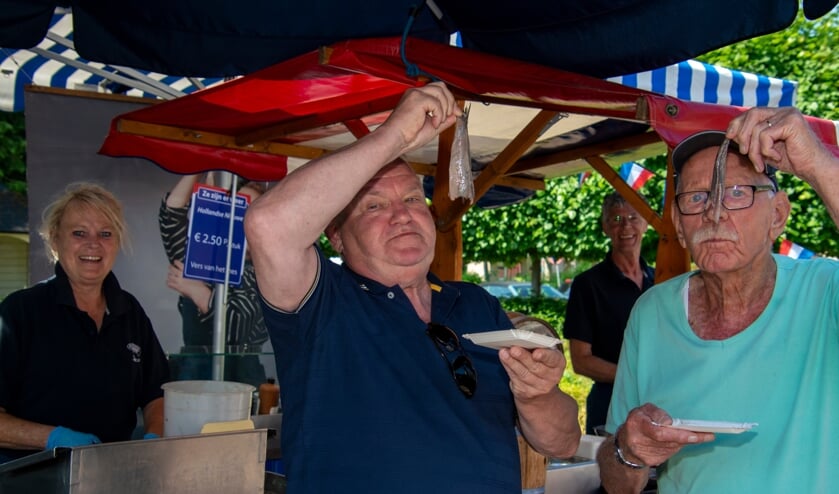 Henk Rozie en Jan Verweij genieten van hun haring. Foto: Marion Verhaaf
