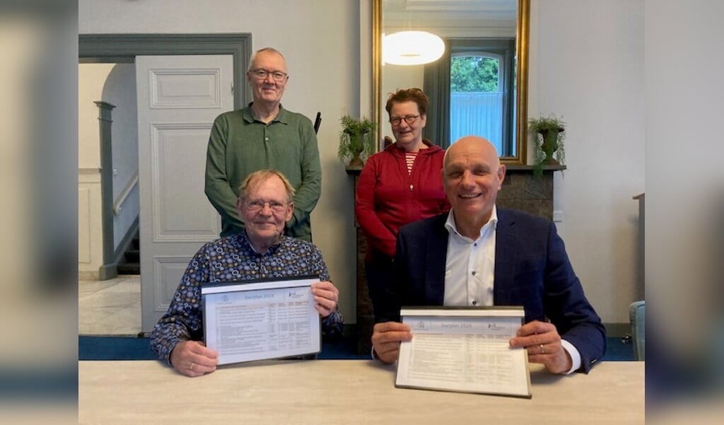 Wethouder Steven van de Graaf (r) en voorzitter Henk Poldermans tekenen het jaarplan onder toeziend oog van bestuursleden Anne Margreet van der Horst en Hay Verstappen.