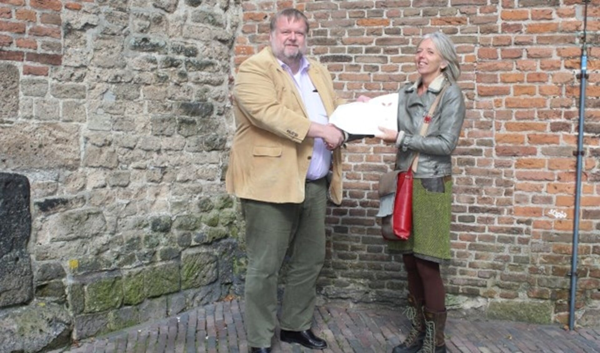 Ron van Bruggen krijgt uit handen van Manja Bente een startpakket voor Walk of Wisdom.