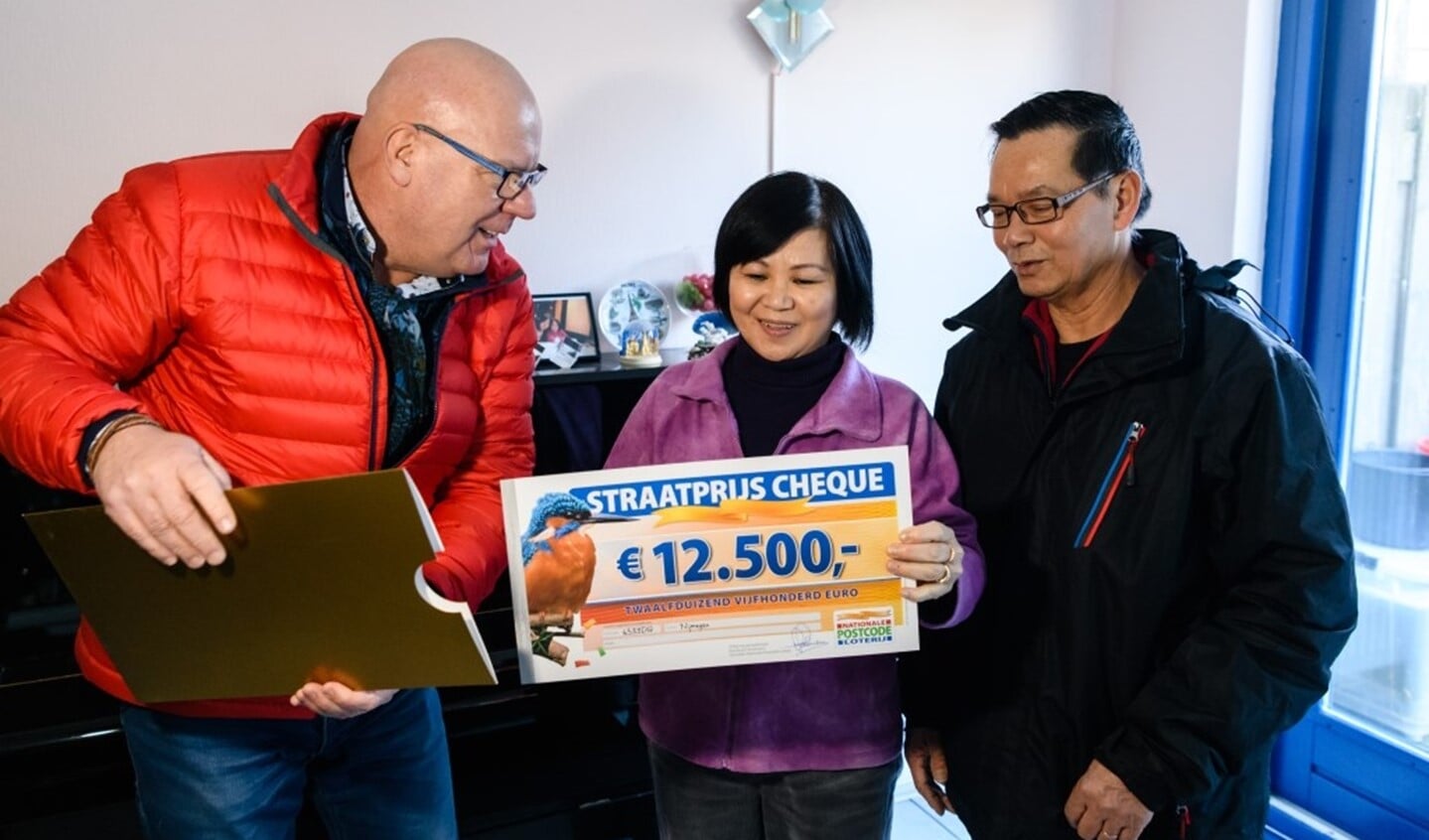 Trao (rechts) en Nga (midden) uit Nijmegen winnen 12.500 euro en worden verrast door Postcode Loterij-ambassadeur Gaston Starreveld met de PostcodeStraatprijs-cheque. (Roy Beusker Fotografie)