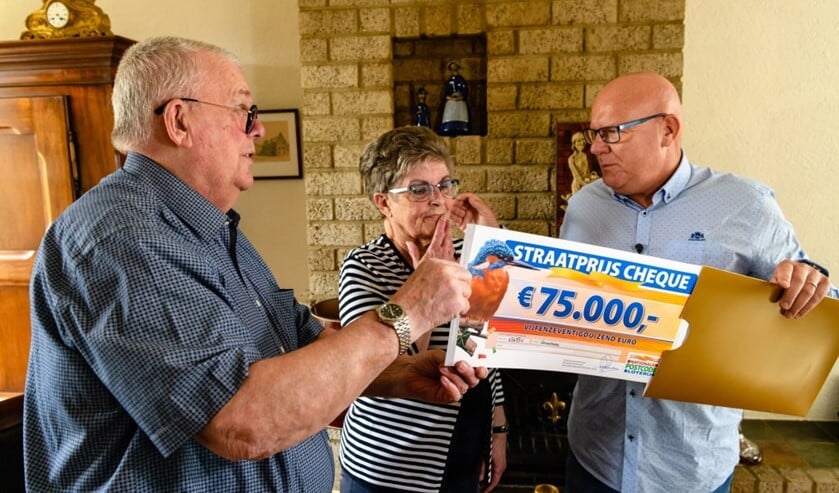 Frans en Wil uit Groesbeek worden verrast door Postcode Loterij-ambassadeur Gaston Starreveld met een PostcodeStraatprijs-cheque van 75.000 euro. (Roy Beusker Fotografie)