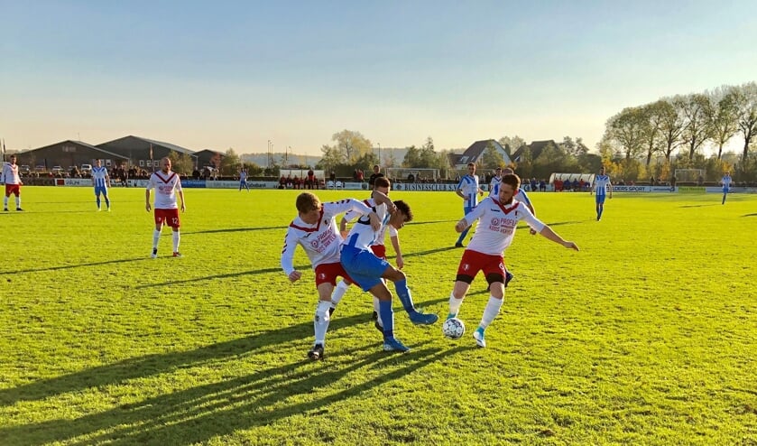 Arnhemse Boys (blauwe broek) in de greep van en bij RKSV Driel. Laatstgenoemde won de derby en kelderkraker van 3D West met liefst 6-1.