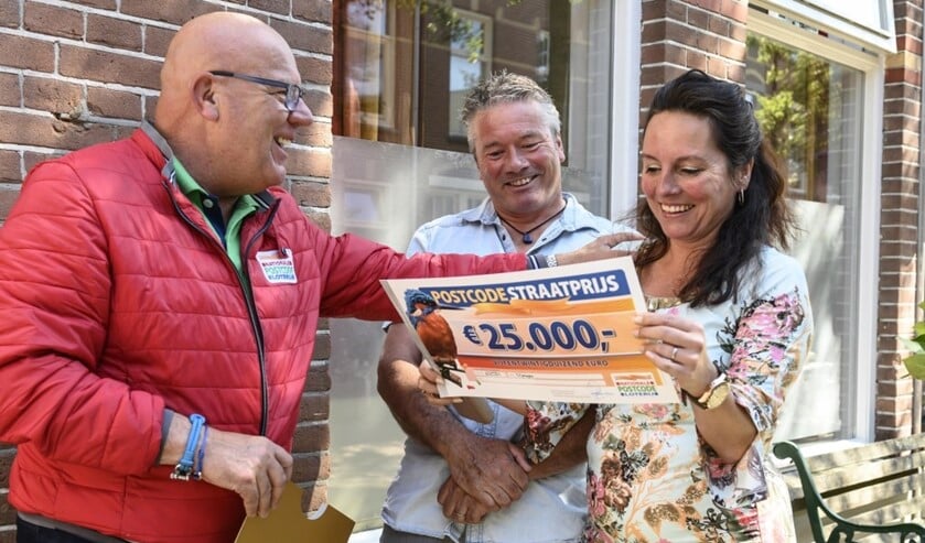 Madelon en haar man Theo nemen de PostcodeStraatprijs-cheque ter waarde van 25.000 euro in ontvangst van Gaston.