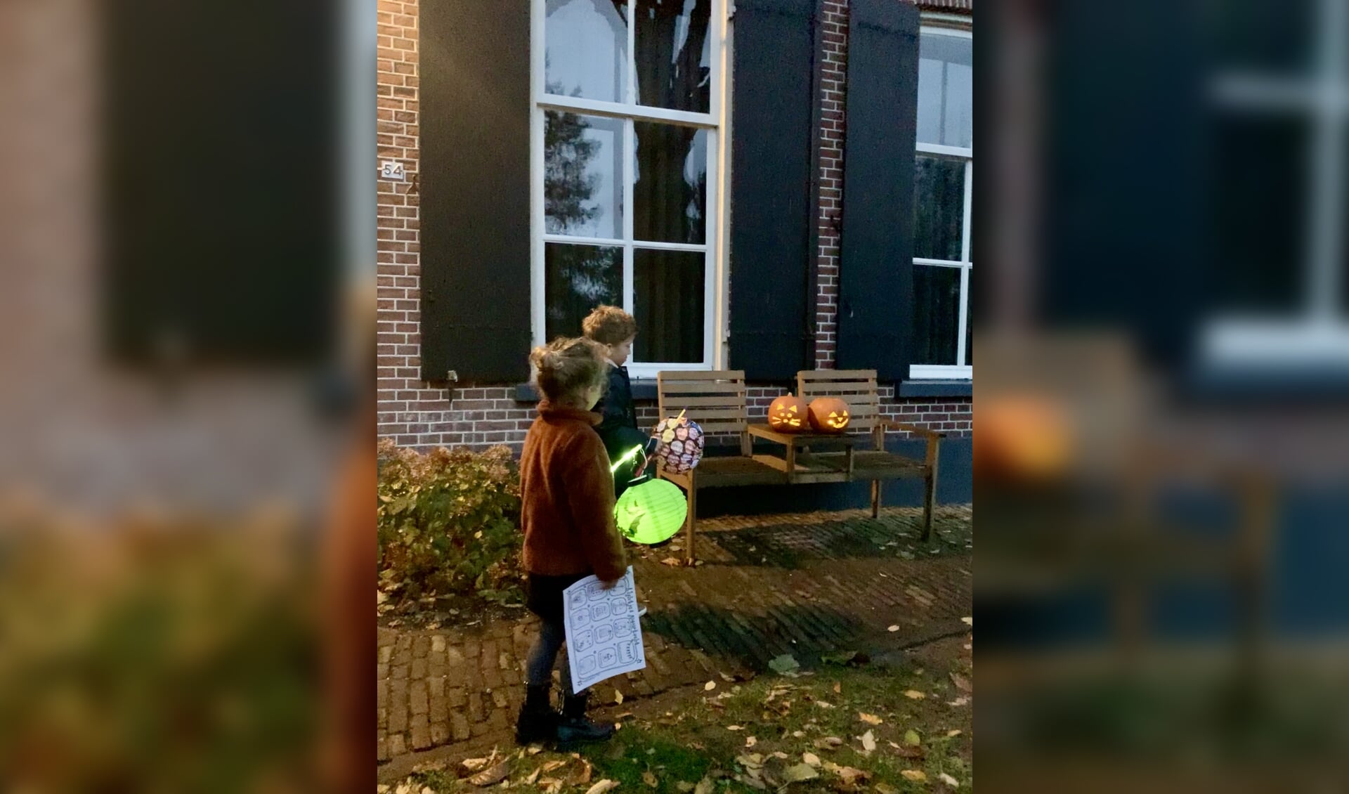 Twee kinderen alvast een rondje door de wijk lopen op zoek naar lichtjes met de zoekkaart in de hand. 
