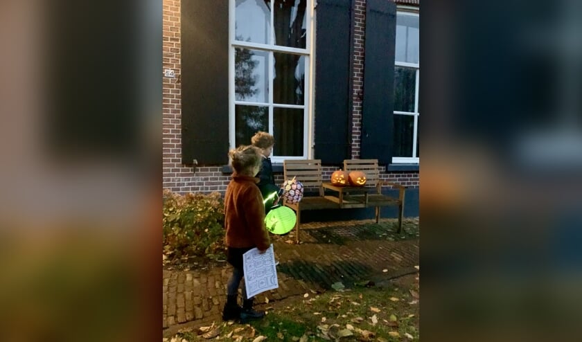 Twee kinderen alvast een rondje door de wijk lopen op zoek naar lichtjes met de zoekkaart in de hand.