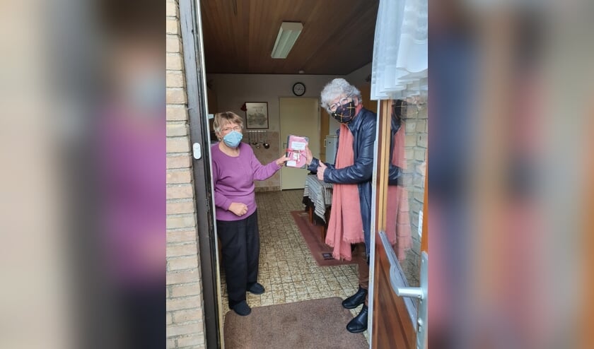 <p>Marion Schouten, vrijwilligster Huiskamer van Elst overhandigt het kookboek aan een blije Ans Schoonderbeek. (foto: Ton Schouten)</p>