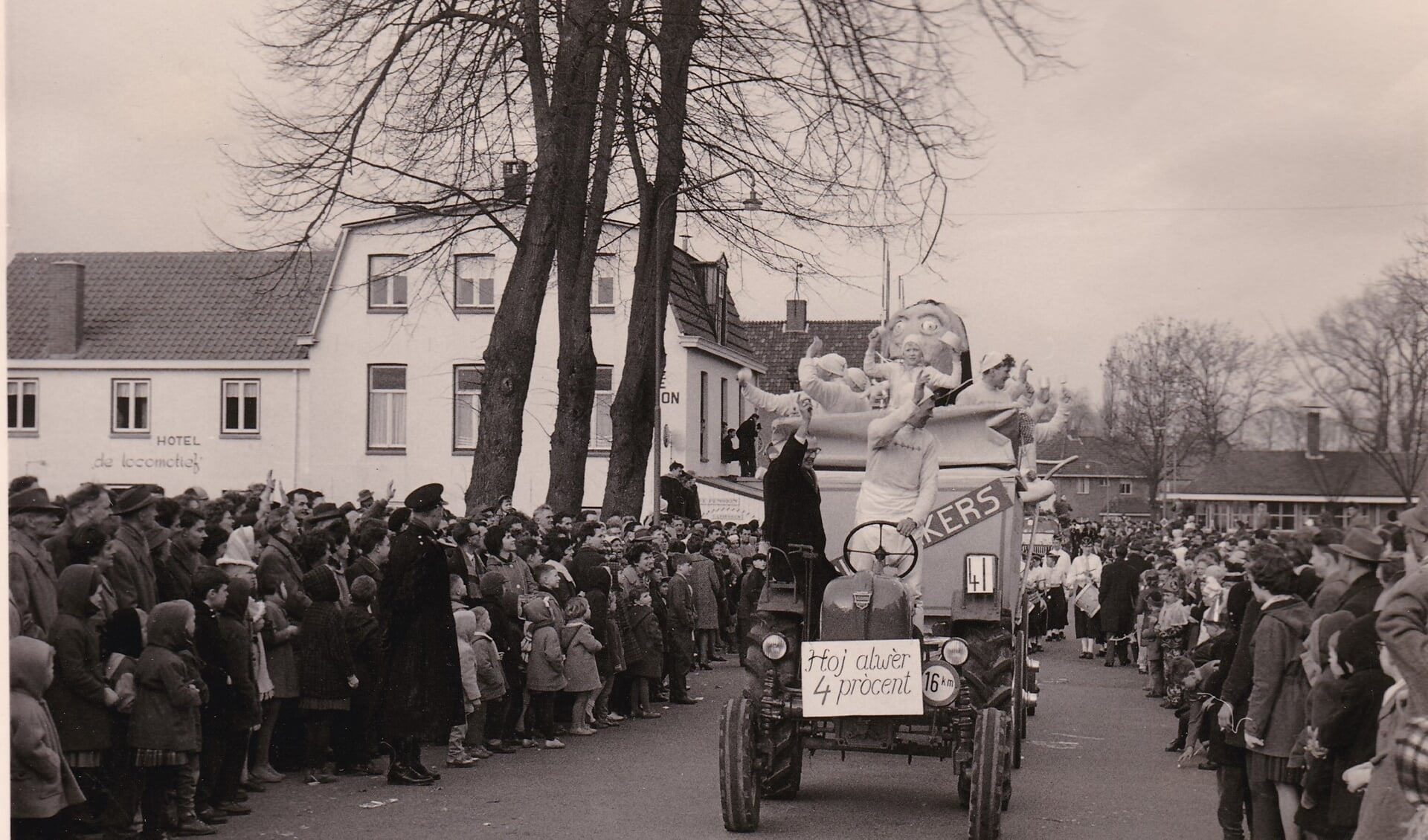 Foto uit 1961. Dorpsstraat ter hoogte huidige gemeentehuis. De carnavalswagen wordt getrokken door een tractor, misschien wel voor het eerst. Achter de wagen loopt de drumband van de schutterij St. Hubertus. (foto: collectie GGD)