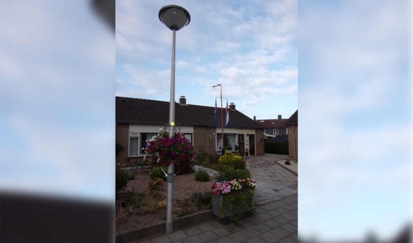 Bloemen aan de lantaarnpaal en bloembak, op de achtergrond de vlaggen. (foto: Jaap Stienstra)