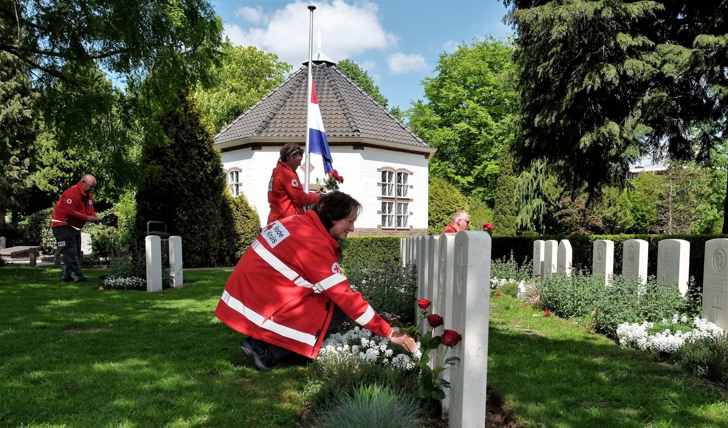 Foto’s van de vrijwilligers die bloemen leggen op de algemene begraafplaats aan de Achterbergsestraatweg in Rhenen.