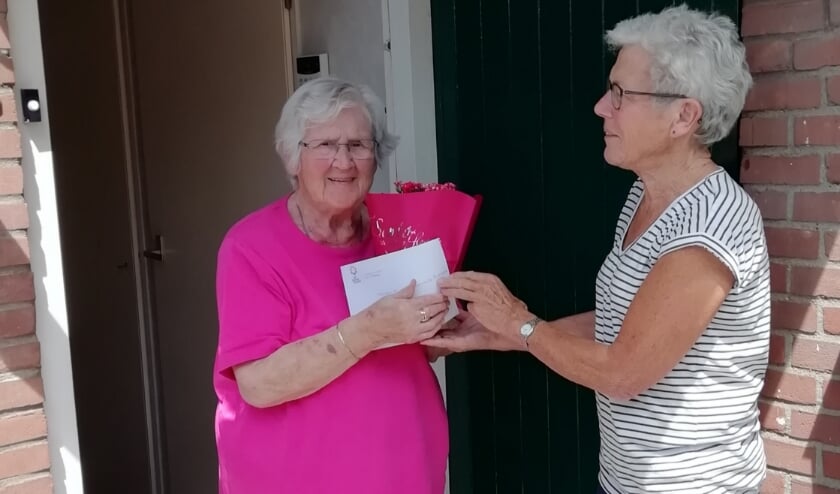Zonnebloemvrijwilliger reikt plantje uit aan gast mevrouw W. van Hasselaar. (foto: Reinolda de Bruin)