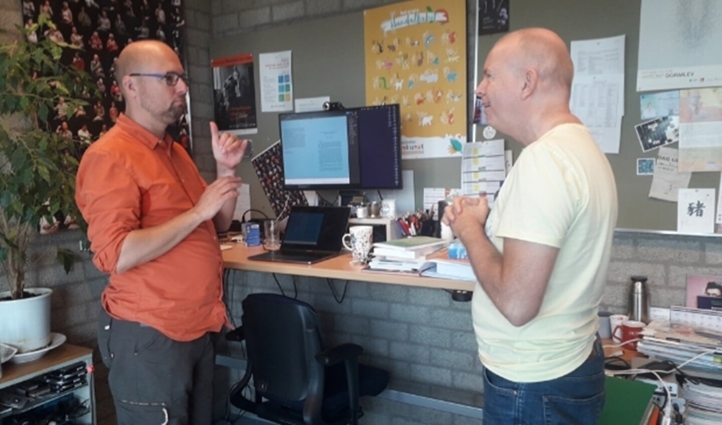 Onno Crasborn (links) ondersteunt zijn spraak met gebaren voor collega-onderzoeker Tom Uittenbogert