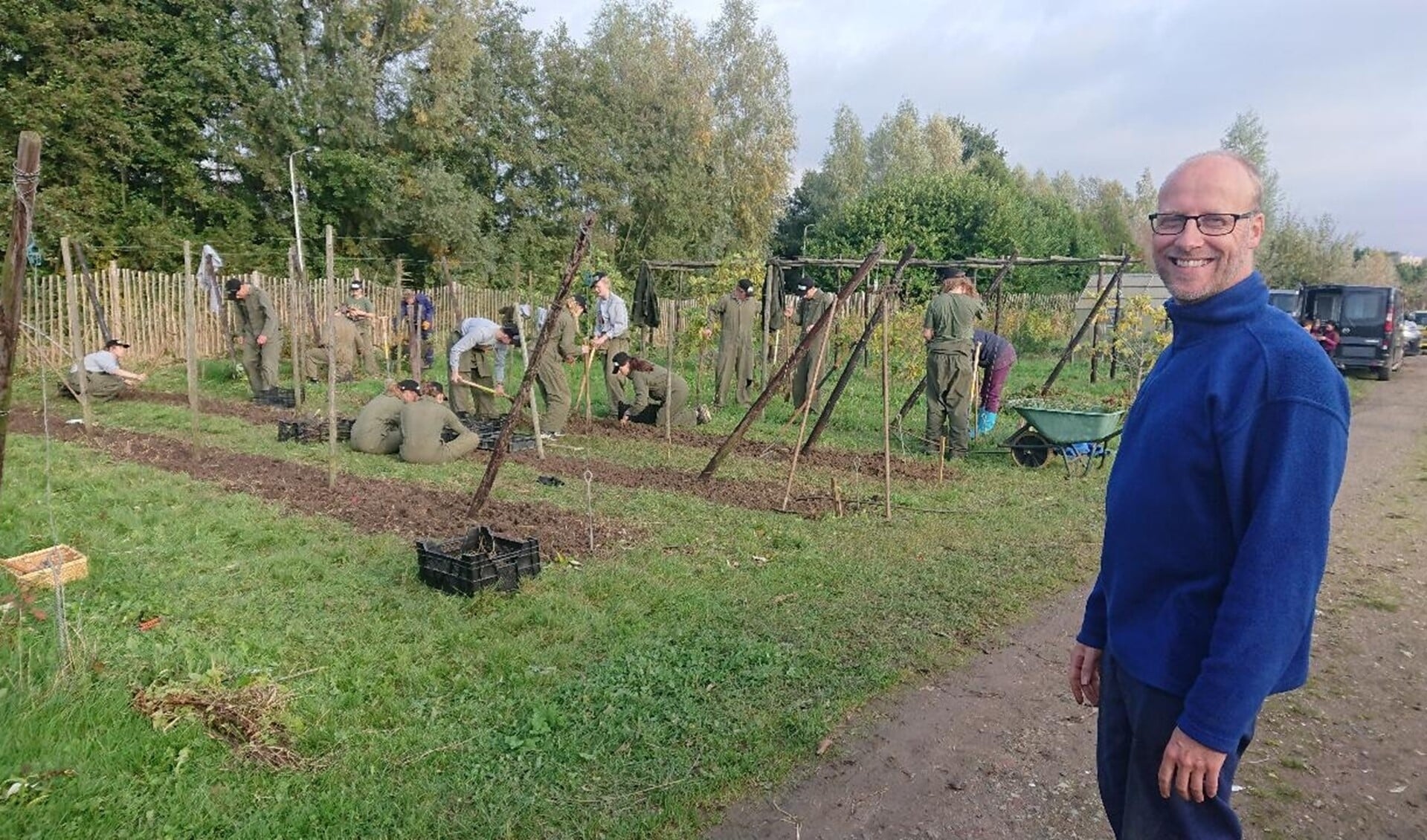 Jongeren maken de grond klaar voor nieuwe bessenstruiken. Henry Witteveen is coördinator van de dag. (Foto: Hilde Wijnen)