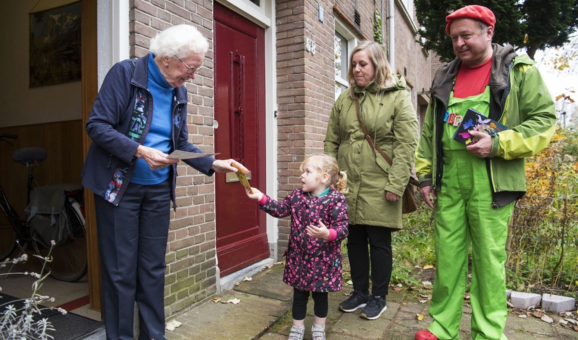 Elisa, de dochter van wethouder Martien Louwers (groene jas), geeft een brief aan mevrouw Doortje van Hest. Rechts de 'postbode'. (Foto Ellen Koelewijn)  