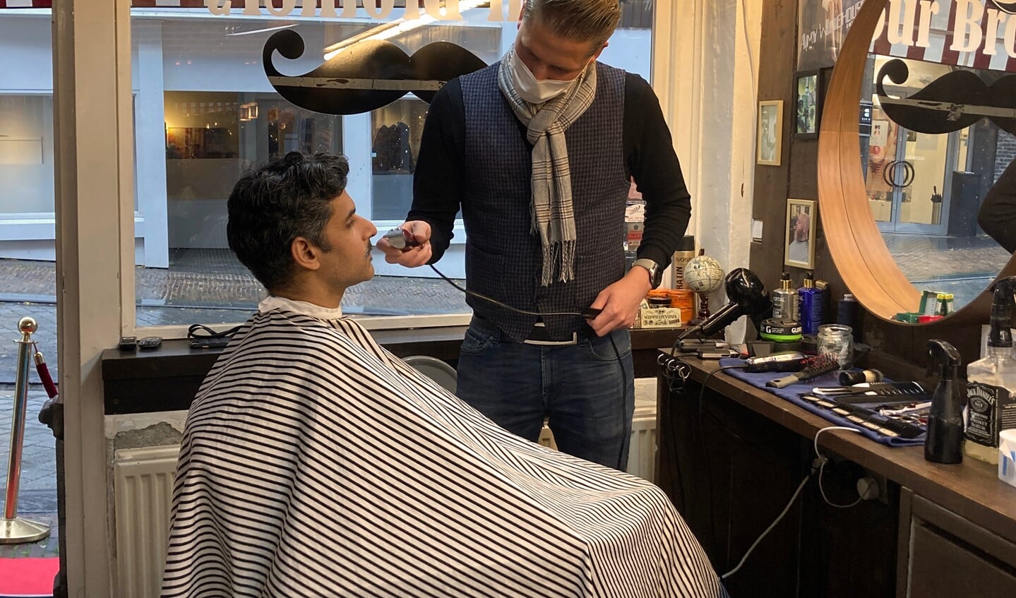 De snor van oncoloog Niven Mehra wordt vakkundig afgeschoren door de professionals van Barbershop Four Brothers.