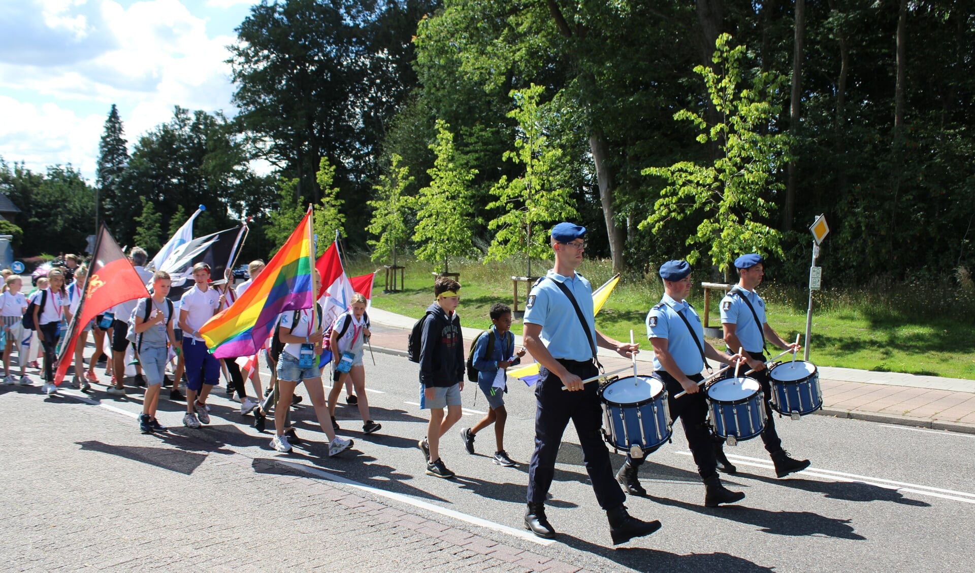 Kinderen lopen in een vlaggenparade met muziek door Groesbeek. (foto: #Vteam)