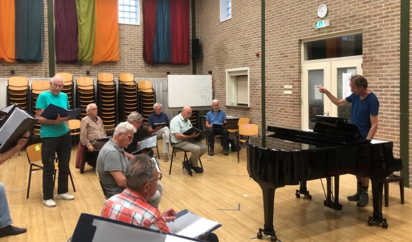 <p>De dirigent en een aantal koorleden op de eerste repetitie na de coronamaatregelen. (foto: Menno Tillema)</p>