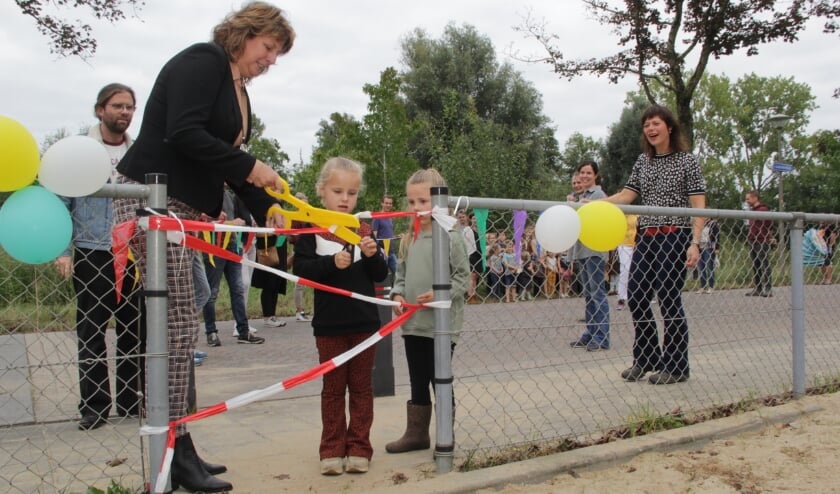 <p>Wethouder Fleuren knipt het lint door bij vernieuwde speelplek in Beek. (foto: Peter Hendriks)</p>