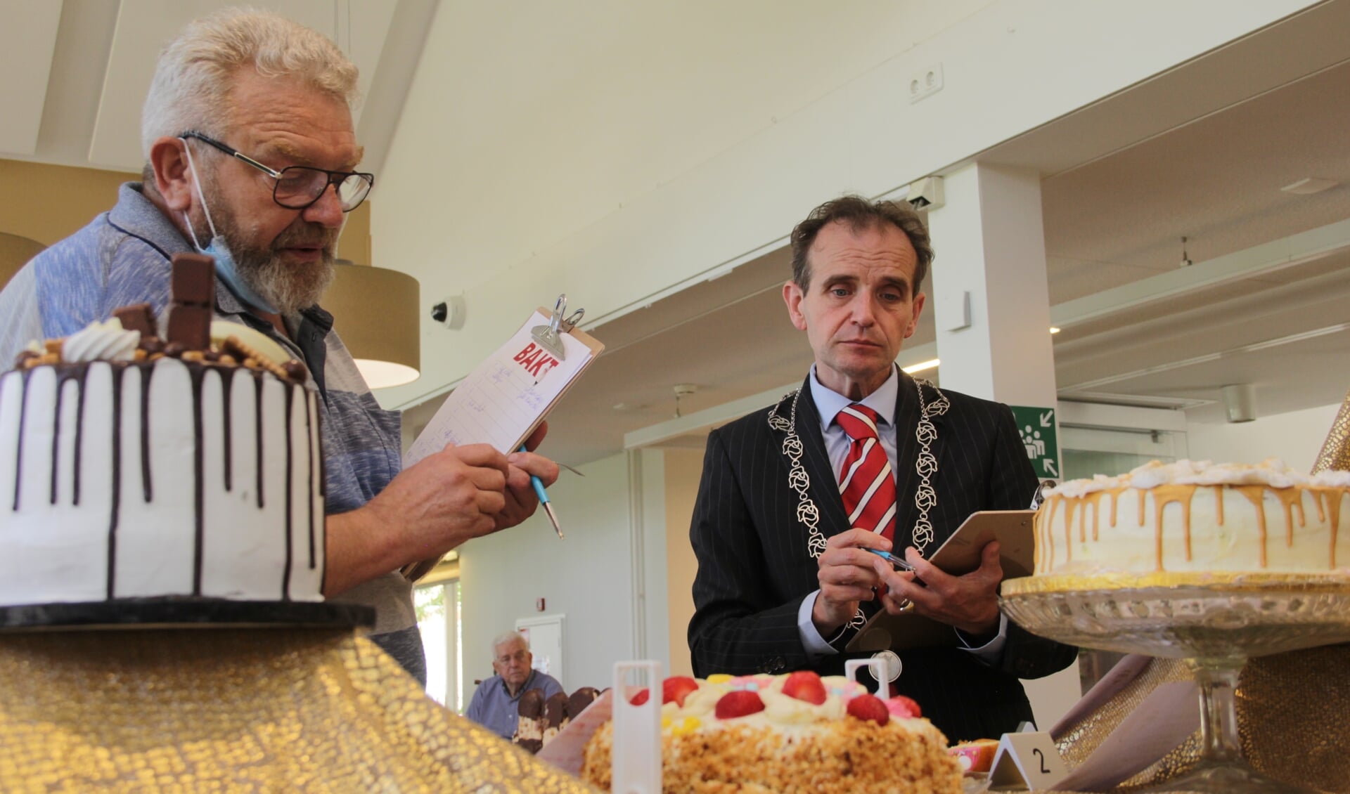 Chef kok Geert Ameel en burgemeester Slinkman jureren de twaalf taarten. (foto: Peter Hendriks)
